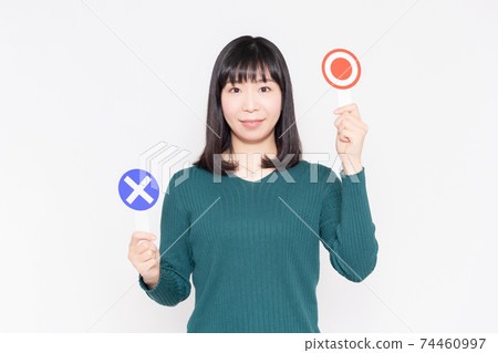 一個女人站在白牆前，舉著OK和NG標語牌 74460997