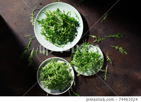 Fresh green raw leaves of arugula rucola salad on dark rustic wooden background. 74461024