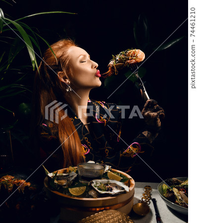 Rich red-haired woman is eating in seafood Rich red-haired woman is eating in seafood 74461210