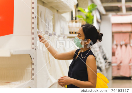 Woman with protective mask shopping in cloth store. Woman with protective mask shopping in cloth store. 74463527