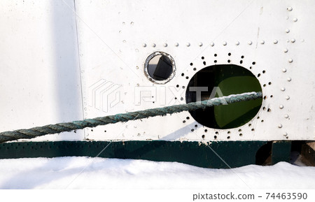 Old ship side with hole and hawser. 74463590