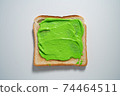 spreading Green paste on a toast on white Background. Top view 74464511