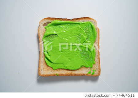 spreading Green paste on a toast on white Background. Top view 74464511