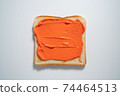spreading Orange paste on a toast on white Background. Top view 74464513