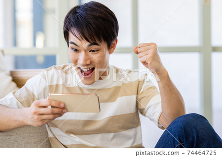A man watching a video on a smartphone A man watching a video on a smartphone 74464725