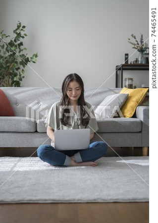 Young woman operating a laptop in the living room 74465491