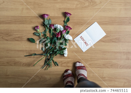 Woman legs in red high heel shoes standing near paper with divorce word on a floor with withered flowers. Concept. Woman legs in red high heel shoes standing near paper with divorce word on a floor with withered flowers. Concept. 74465511