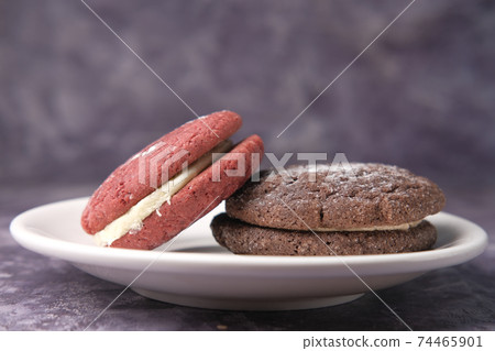 chocolate and red vanilla cookies on plate against black background  74465901
