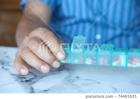 senior man's hands taking medicine from a pill box senior man's hands taking medicine from a pill box 74465935