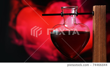 Open heart-shaped bottle of red love potion on a blurred background 74466844