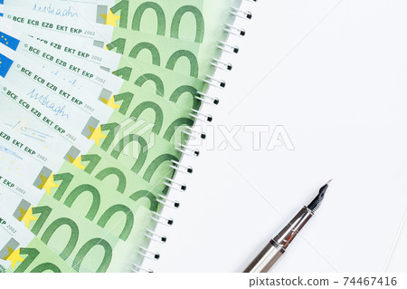 100 euro banknotes with empty notepad and pen on white background 74467416