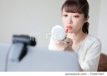 A young woman fixing her makeup between web conferences A young woman fixing her makeup between web conferences 74467467