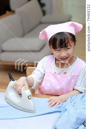A 5-year-old girl helping to iron a shirt A 5-year-old girl helping to iron a shirt 74468152