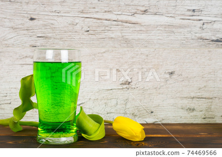 green beer in glass with tulip on rustic table 74469566