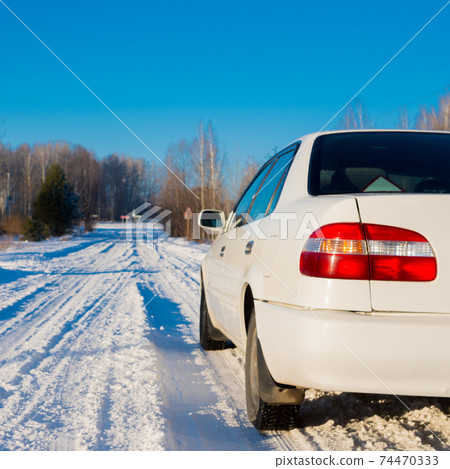 white car on winter snowy country road, rear closeup view white car on winter snowy country road, rear closeup view 74470333