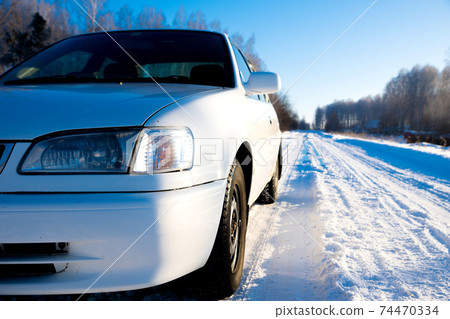 white car on winter snowy country road, front closeup view white car on winter snowy country road, front closeup view 74470334