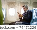 Caucasian businessman mobile checking work or news on airplane cabin. man watching movie or entertainment media waiting for inflight service. working or travel abroad concept 74471226