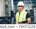 Portrait of engineer foreman holding clipboard in industrial factory. worker in safety uniform working at construction site. heavy machine technology industry concept. copy space 74471228