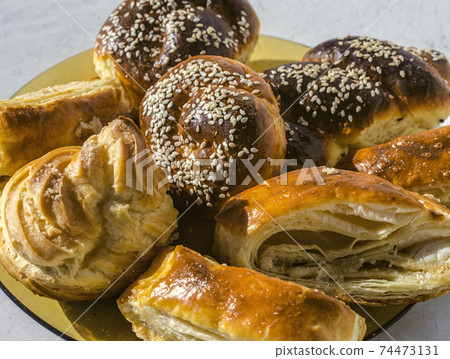 Yellow ceramic plate with sesame buns, Gata and Eclair on an old table Yellow ceramic plate with sesame buns, Gata and Eclair on an old table 74473131