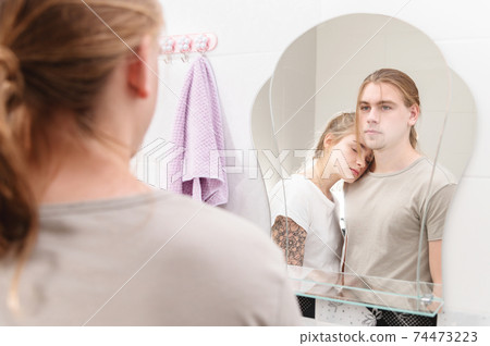 A young couple of millennials embrace by the bathroom mirror. Young family life 74473223