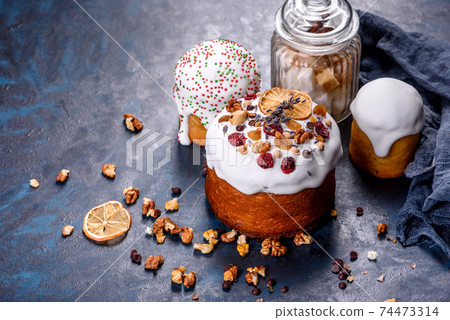 Festive cakes with white glaze, nuts and raisins with Easter eggs on the festive table Festive cakes with white glaze, nuts and raisins with Easter eggs on the festive table 74473314