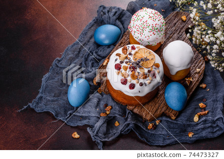 Festive cakes with white glaze, nuts and raisins with Easter eggs on the festive table Festive cakes with white glaze, nuts and raisins with Easter eggs on the festive table 74473327