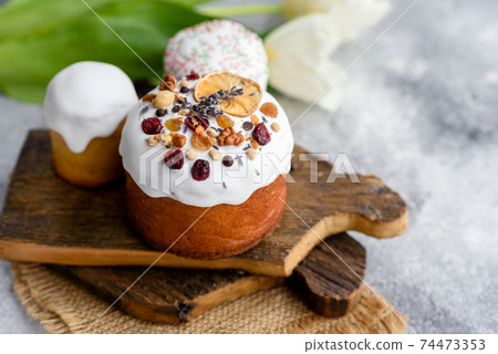 Festive cakes with white glaze, nuts and raisins with Easter eggs on the festive table Festive cakes with white glaze, nuts and raisins with Easter eggs on the festive table 74473353