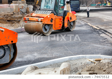 Two large vibratory road rollers are working on a construction site, compacting fresh asphalt. 74473512