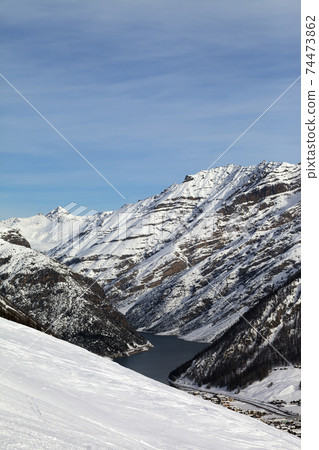 Off piste ski slope, snowy high mountains with forest, big lake Off piste ski slope, snowy high mountains with forest, big lake 74473862