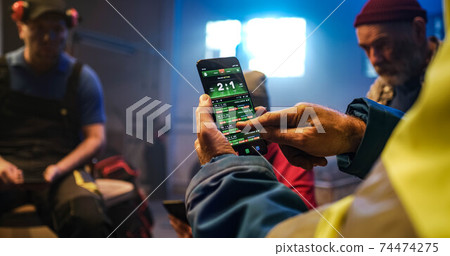 Elderly man making bets and watching match with friends 74474275