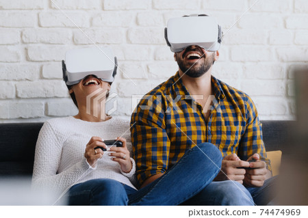 Young Couple Playing Virtual Reality With Headset On Sofa Young Couple Playing Virtual Reality With Headset On Sofa 74474969