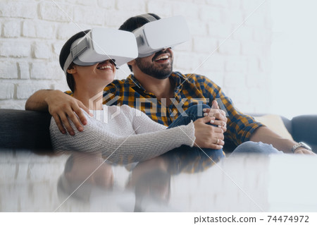 Young Couple Playing Virtual Reality With Headset On Sofa Young Couple Playing Virtual Reality With Headset On Sofa 74474972