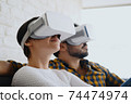 Young Couple Playing Virtual Reality With Headset On Sofa 74474974