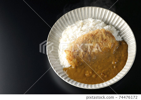A hot cutlet curry with a large pork cutlet in the middle taken on a black background (overhead view) 74476172