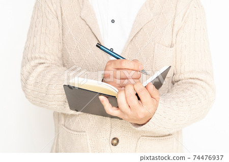 A man writing notes in a notebook 74476937