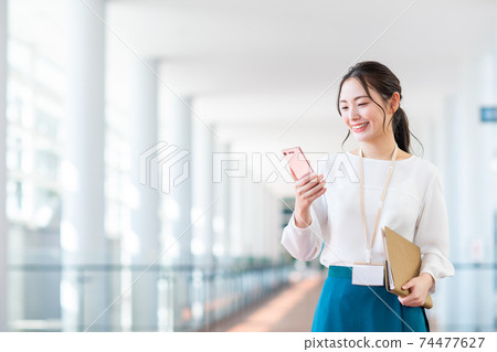 Business woman in an office with a smartphone Business woman in an office with a smartphone 74477627