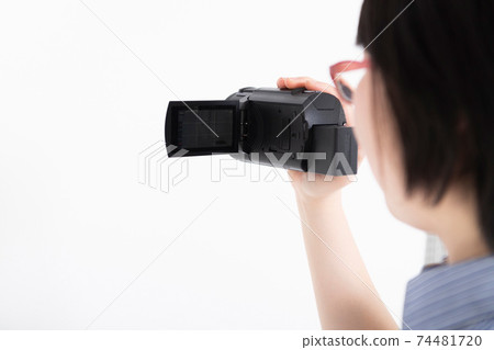 A woman shooting a video with a video camera A woman shooting a video with a video camera 74481720