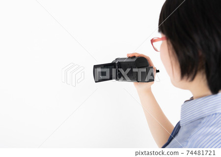 A woman shooting a video with a video camera A woman shooting a video with a video camera 74481721