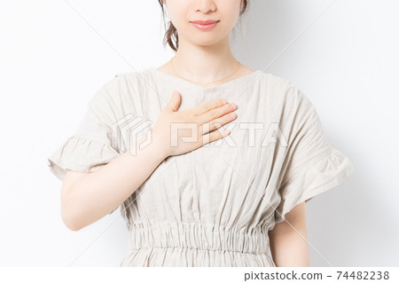 站立在白色背景前面和把她的手放的少婦在她的胸口上 74482238