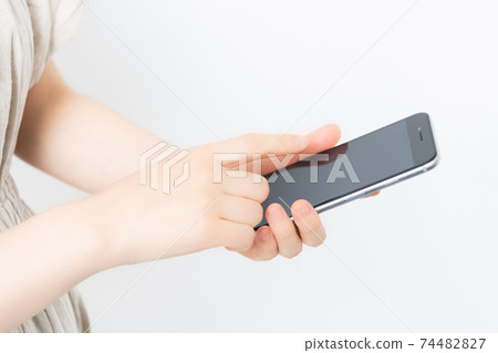 站立在白色背景前面和拿著智能手機的少婦 74482827