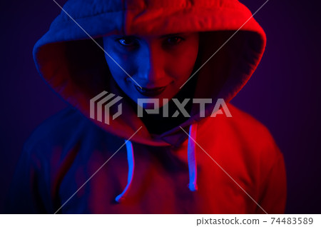 Portrait of a beautiful young woman in a sweatshirt with a hood in neon light 74483589