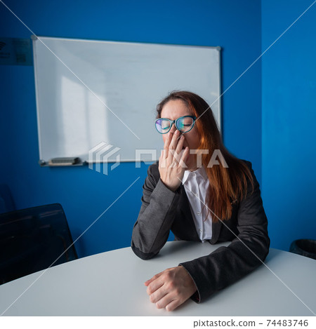 A woman in a suit and glasses makes yawns in the conference room. A female office manager with chronic fatigue sits at a table in a boring workshop. Partners are late for a business meeting. A woman in a suit and glasses makes yawns in the conference room. A female office manager with chronic fatigue sits at a table in a boring workshop. Partners are late for a business meeting. 74483746