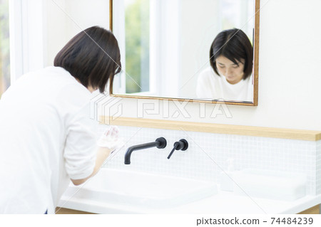Woman washing hands with soap 74484239