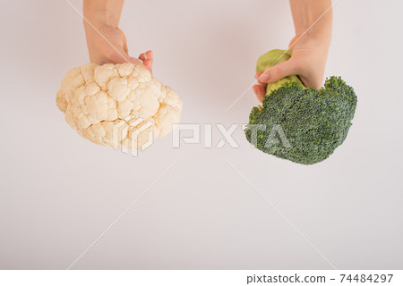 Broccoli and cauliflower in female hands on a white background. Empty space. 74484297