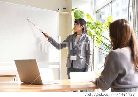 Female seminar instructor explaining on the whiteboard Female seminar instructor explaining on the whiteboard 74484455