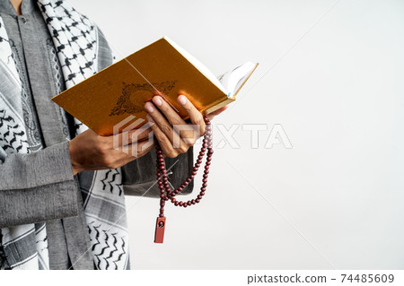 male gesture holding quran and prayer beads 74485609