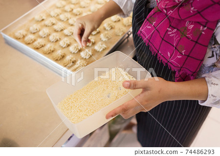 hand put a cheese topping on semprit cake 74486293