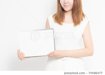 Young woman with sketchbook in front of white background 74486477