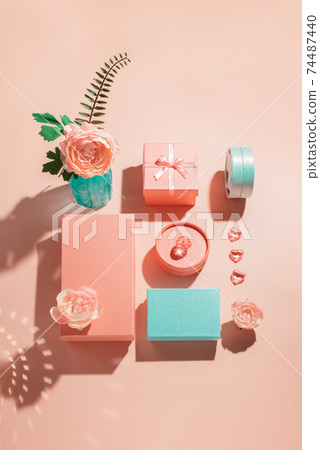 Festive geometric arrangement of gift boxes and flowers in pastel colors with sunny shadows 74487440