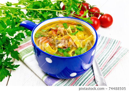 Soup with mung and noodles in blue bowl on napkin Soup with mung and noodles in blue bowl on napkin 74488505